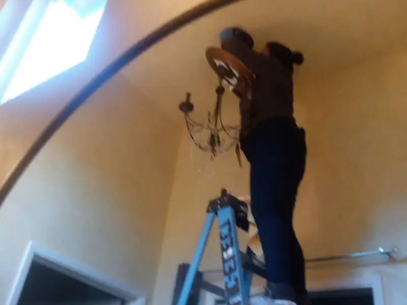 Electrician installing a chandelier in a Clermont residence